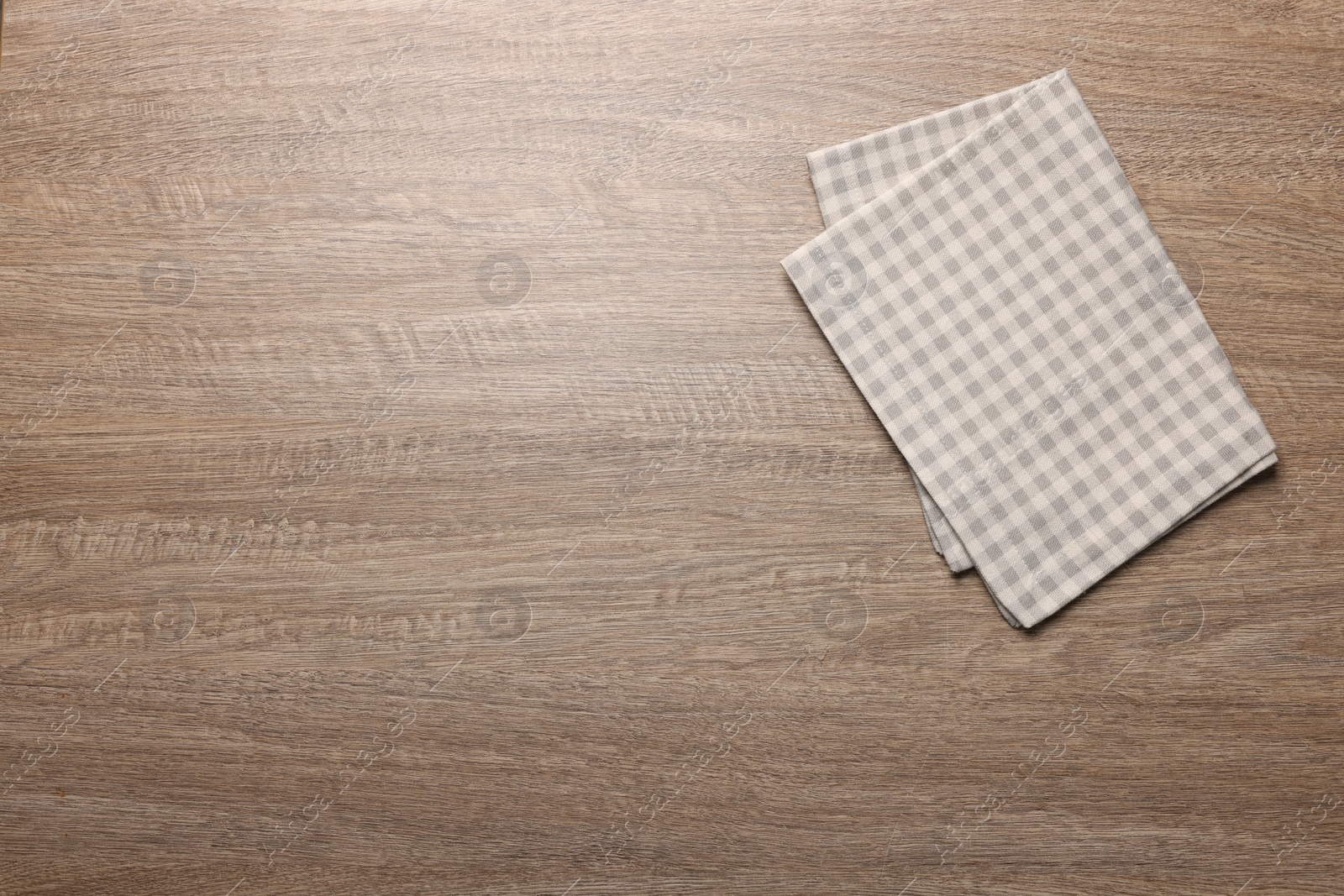 Photo of Checkered tablecloth on wooden table, top view. Space for text