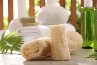 Photo of Natural loofah sponges on grey textured table