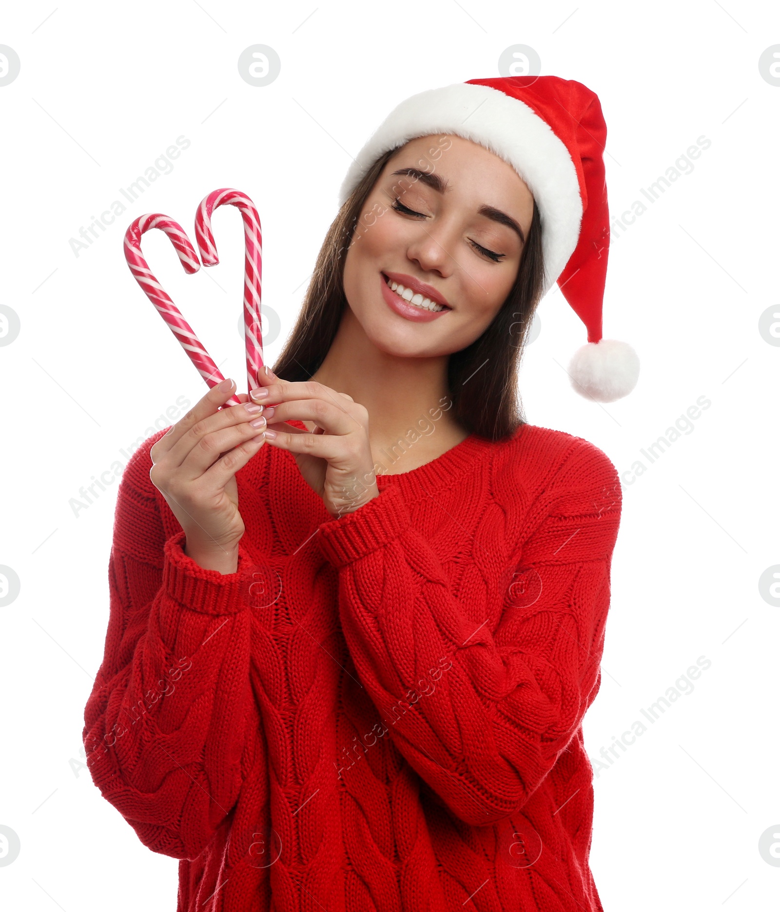 Photo of Young woman in red sweater and Santa hat holding candy canes on white background