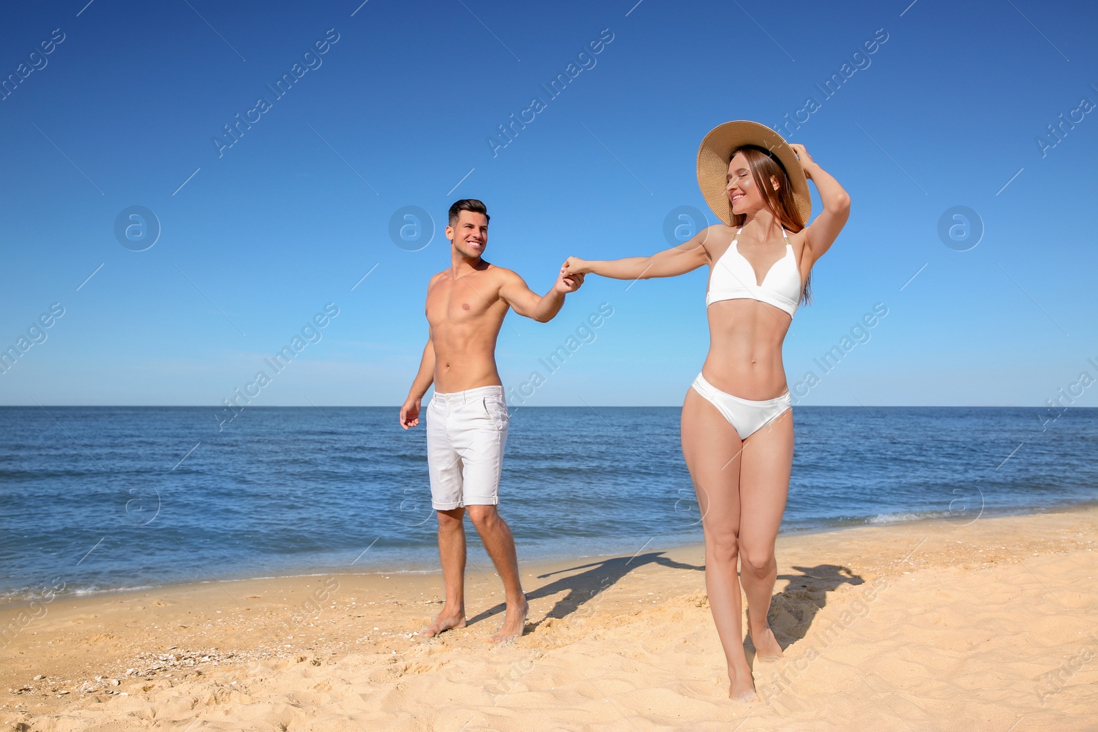 Photo of Woman in bikini and her boyfriend on beach. Happy couple