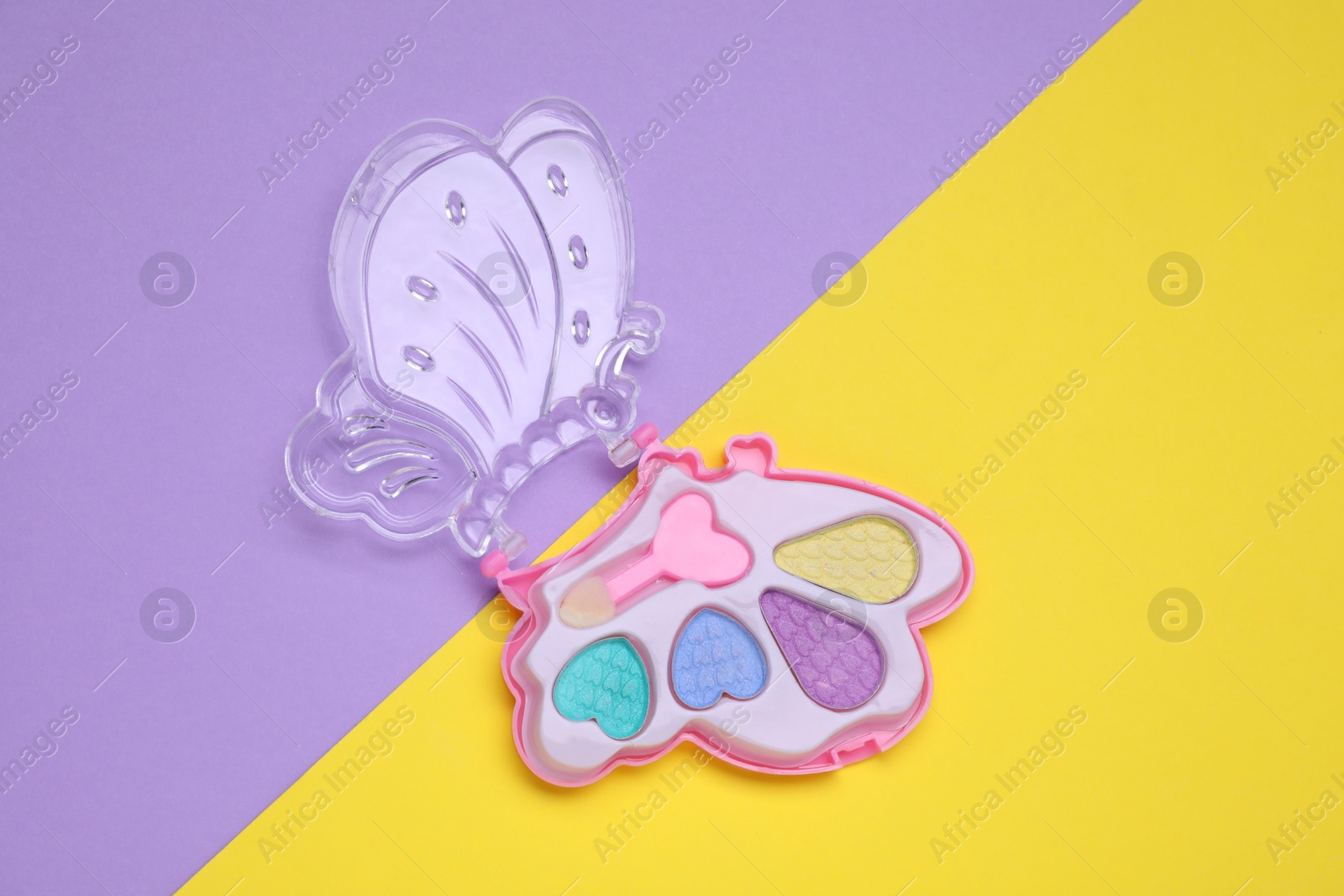 Photo of Children's eye shadow palette with brush on color background, top view