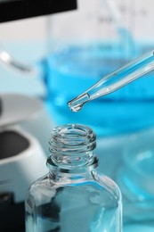 Dripping liquid from pipette into bottle in laboratory, closeup