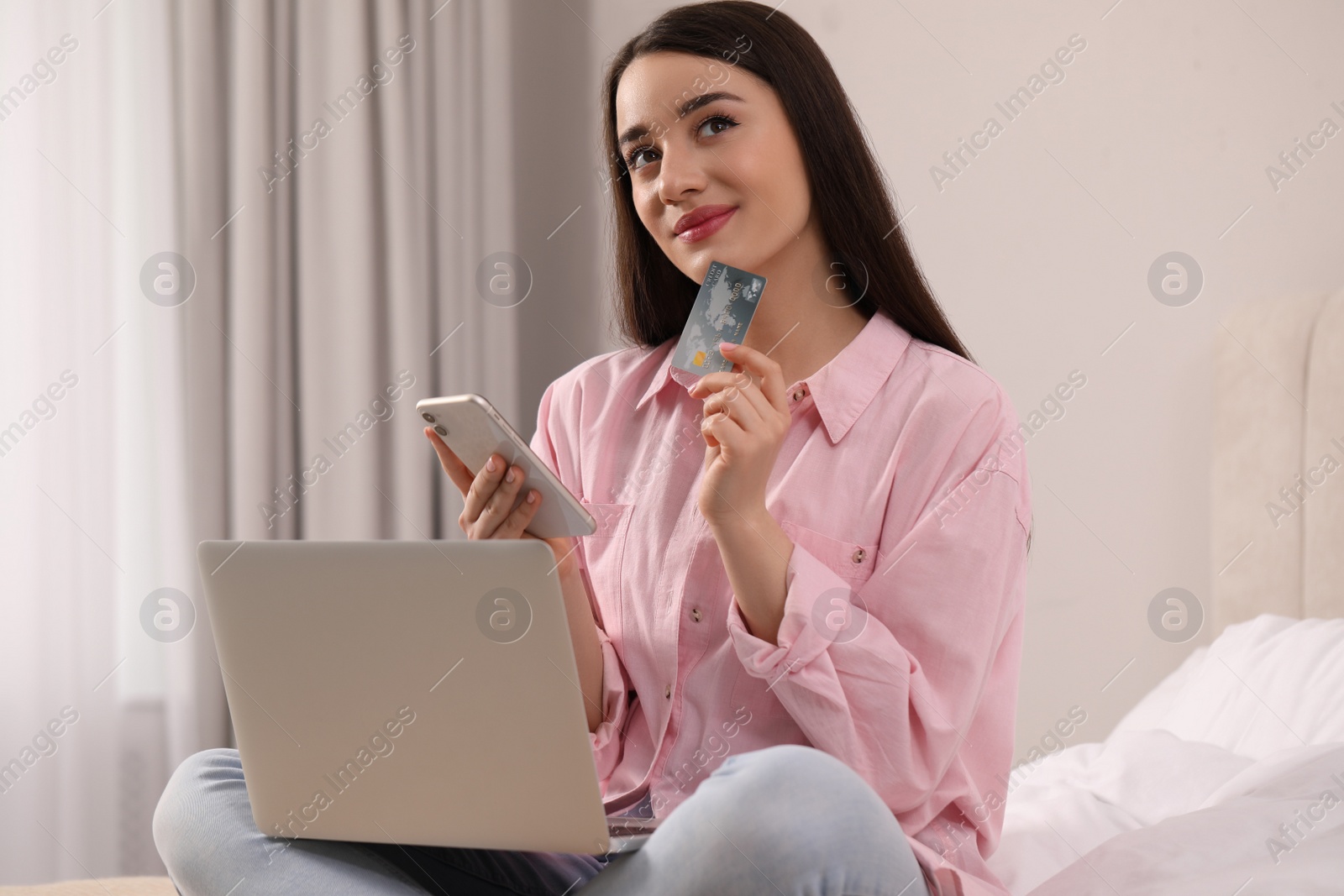 Photo of Woman with credit card using laptop and smartphone for online shopping at home