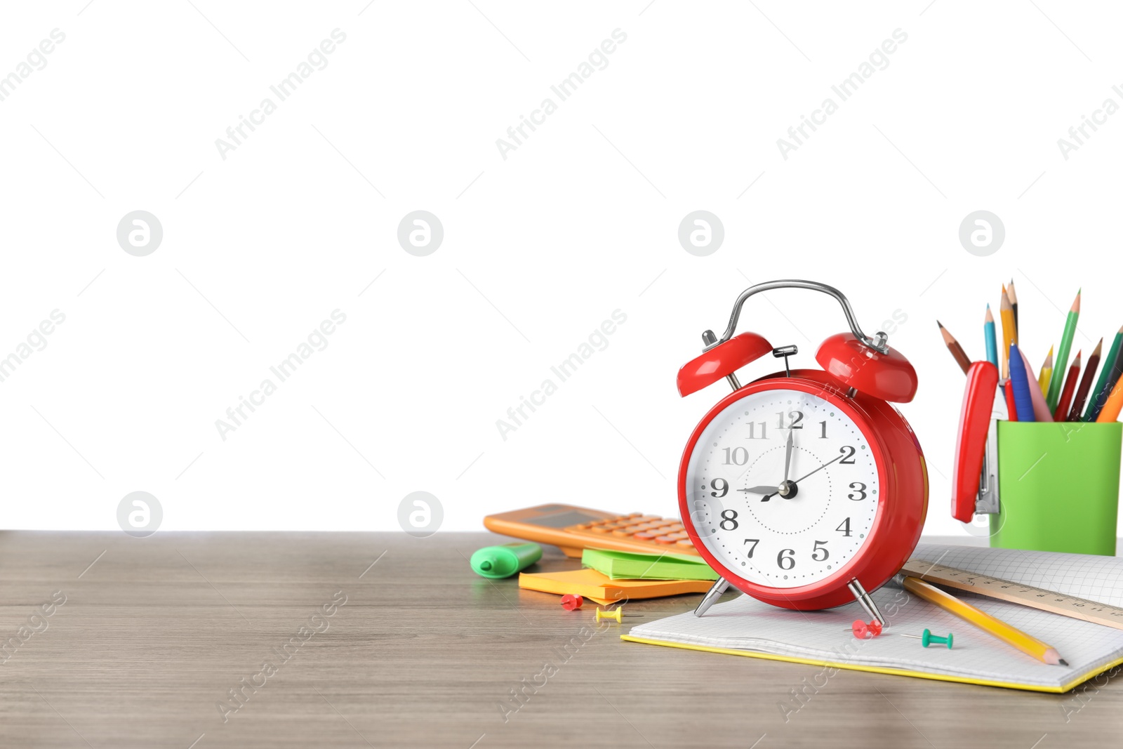 Photo of Red alarm clock and different stationery on wooden table against white background, space for text. School time