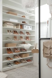 Photo of Dressing room interior with stylish shoes and accessories on shelves