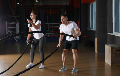 Couple working out with battle ropes in gym