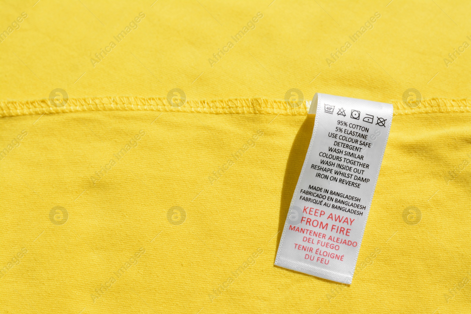 Photo of Clothing label on yellow garment, top view, Space for text