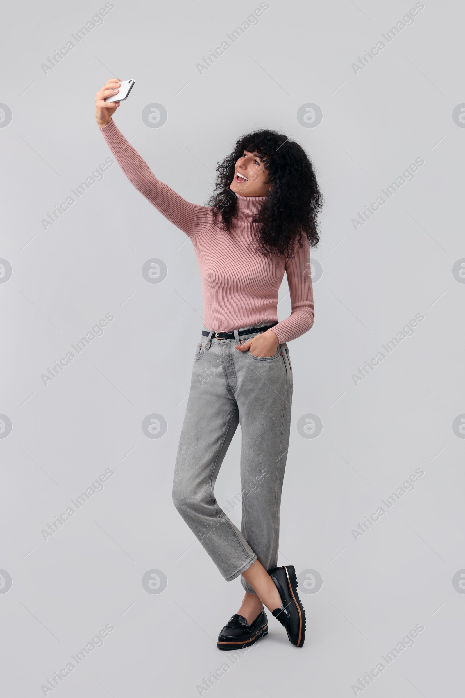 Photo of Beautiful young woman taking selfie on light grey background