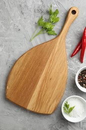 Photo of Cutting board, salt, spices, chili peppers and parsley on grey textured table, flat lay. Space for text