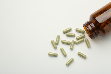 Photo of Bottle and vitamin capsules on white background, flat lay. Space for text