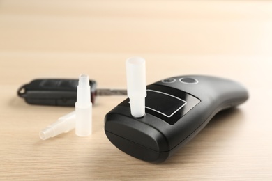 Photo of Modern breathalyzer and mouthpieces on wooden table