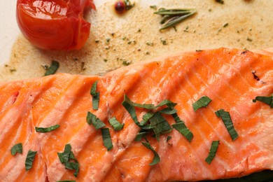 Tasty grilled salmon with tomato and spices on plate, top view