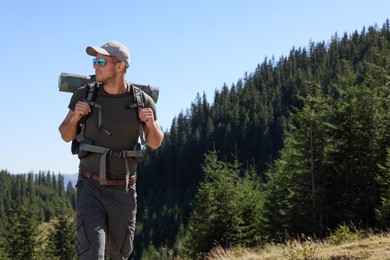 Photo of Tourist with backpack in mountains on sunny day. Space for text