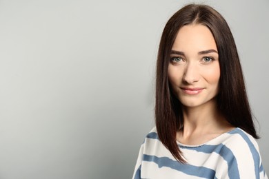 Photo of Portrait of pretty young woman with gorgeous chestnut hair on light grey background, space for text