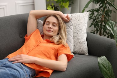 Photo of Woman napping on sofa in room with green houseplants