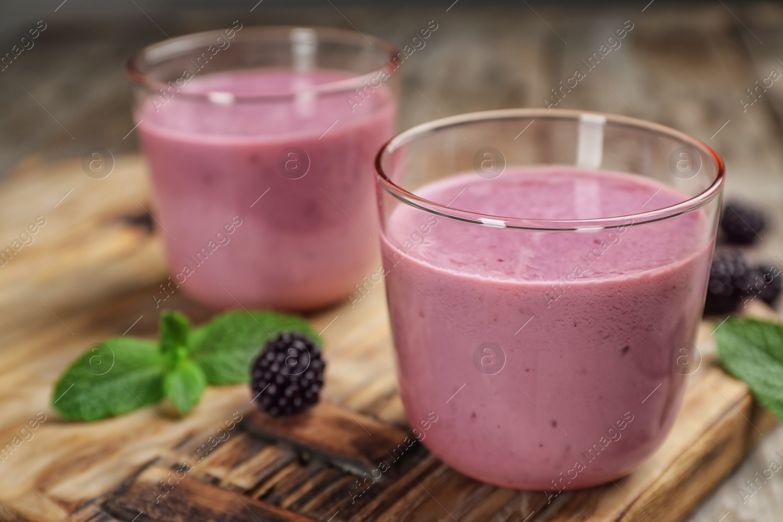 Photo of Glasses with blackberry yogurt smoothies on wooden board
