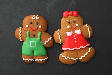 Photo of Gingerbread man and woman on black table, flat lay. Delicious Christmas cookies