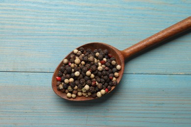 Photo of Aromatic spice. Different peppers in spoon on light blue wooden table, top view