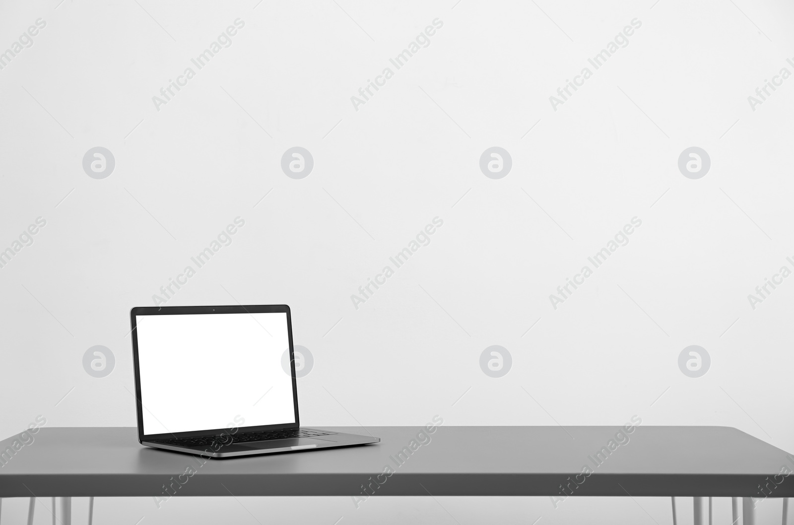 Photo of Modern laptop with blank screen on table against light background