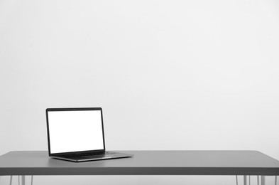 Modern laptop with blank screen on table against light background