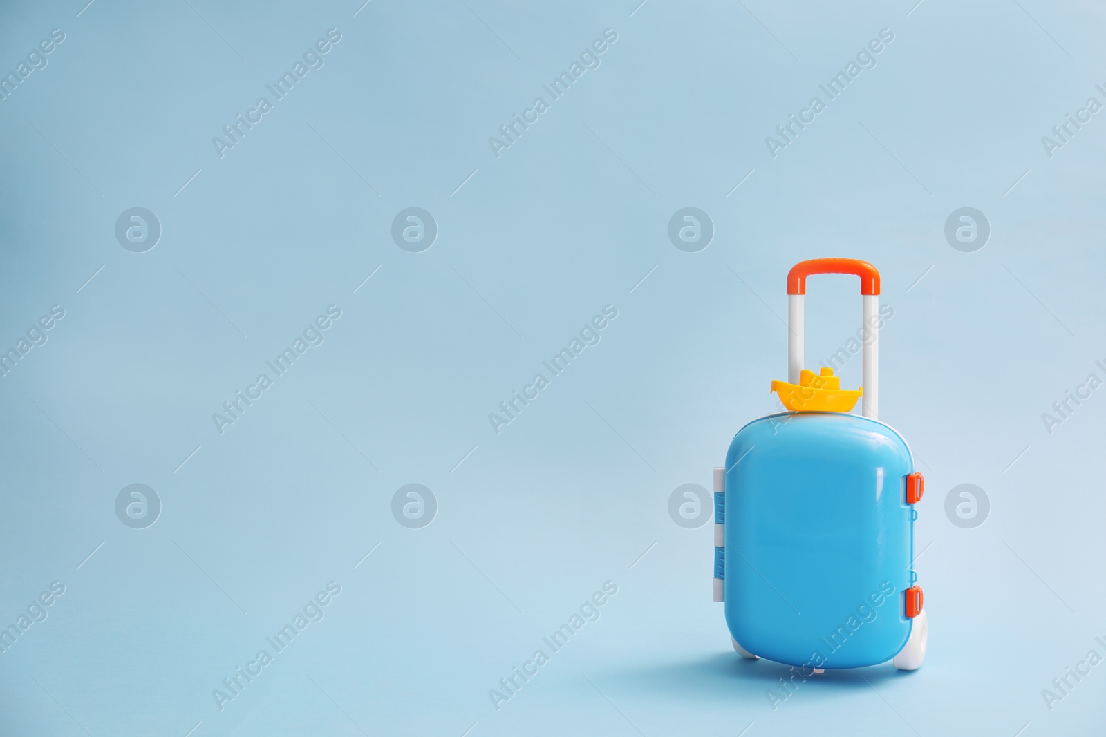 Photo of Stylish child suitcase with toy on blue background, space for text