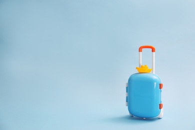 Stylish child suitcase with toy on blue background, space for text