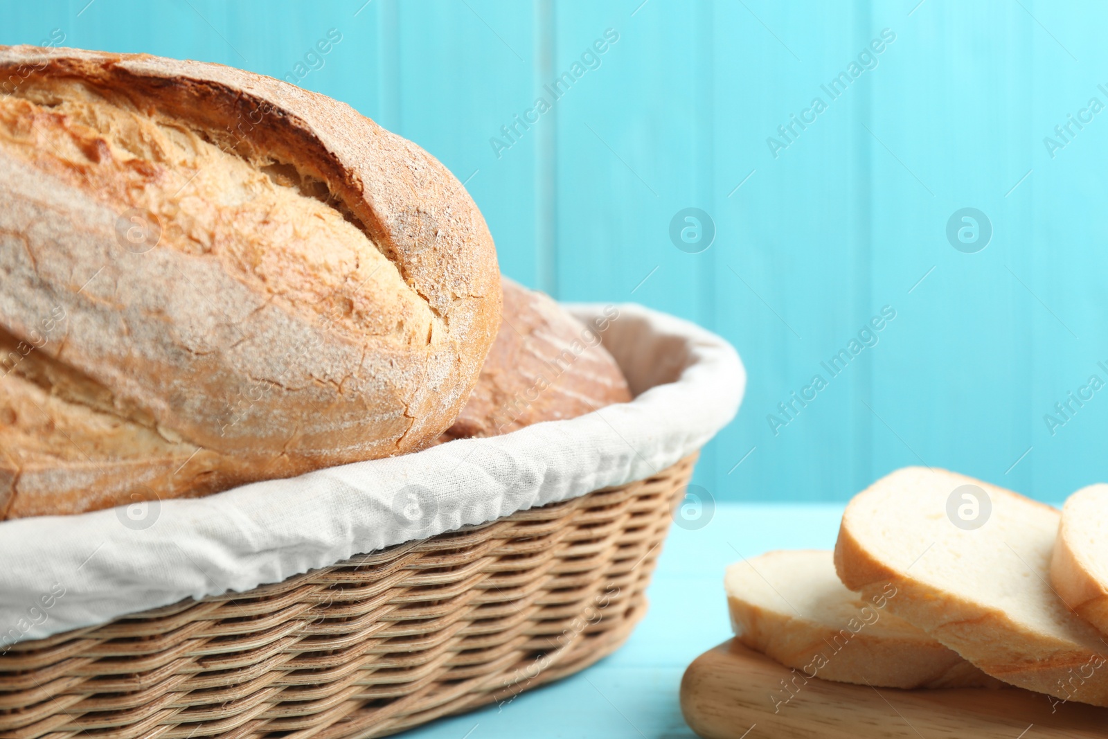 Photo of Tasty fresh bread on light blue wooden table, closeup