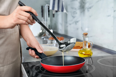 Photo of Woman cooking delicious thin pancakes on induction stove, closeup