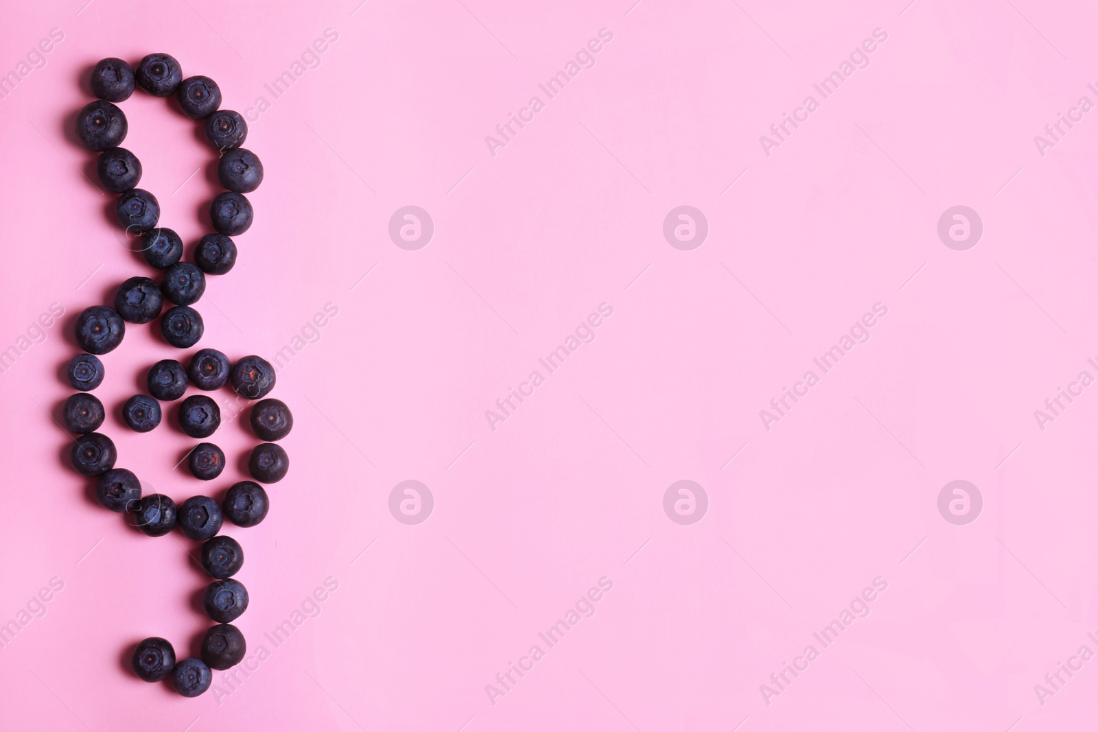 Photo of Treble clef made of bilberries on color background, top view with space for text. Creative musical notes