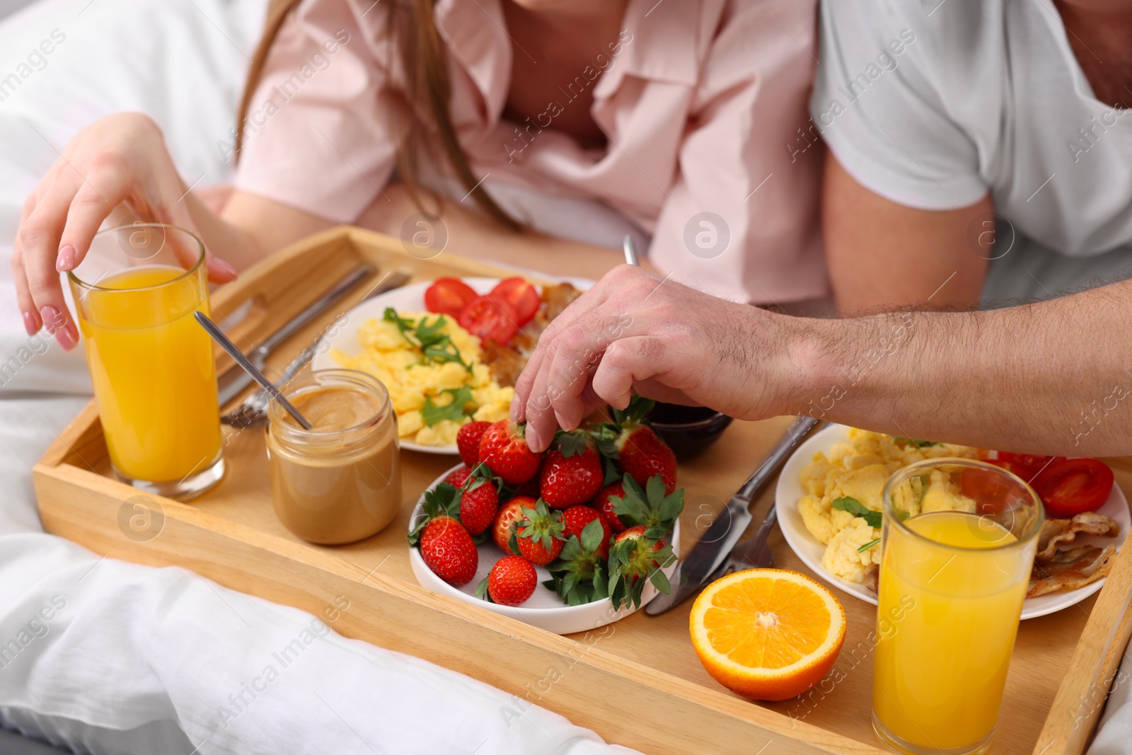 Photo of Couple eating tasty breakfast on bed, closeup