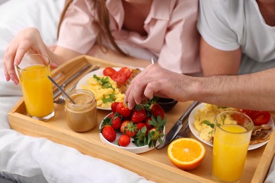 Couple eating tasty breakfast on bed, closeup