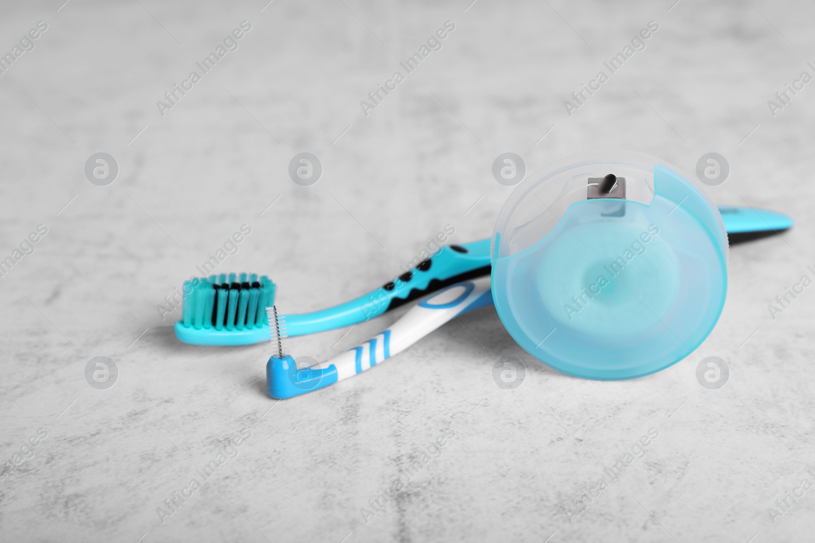 Photo of Container with dental floss and toothbrushes on light grey textured table