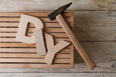 Photo of Abbreviation DIY made of letters, crate and hammer on wooden table, flat lay