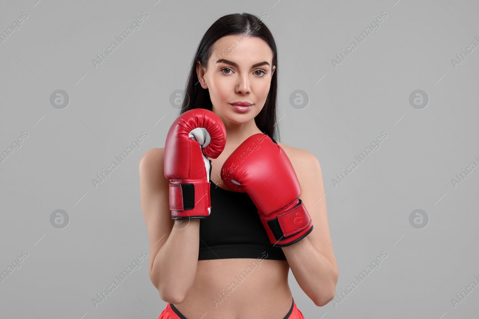 Photo of Portrait of beautiful woman in boxing gloves on grey background