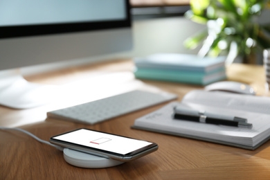 Photo of Modern workplace and smartphone charging with wireless pad