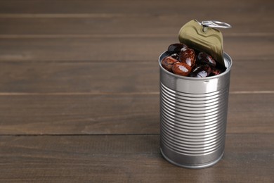 Photo of Tin can with kidney beans on wooden table, space for text