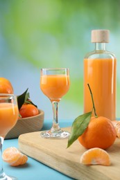Photo of Delicious tangerine liqueur and fresh fruits on light blue table