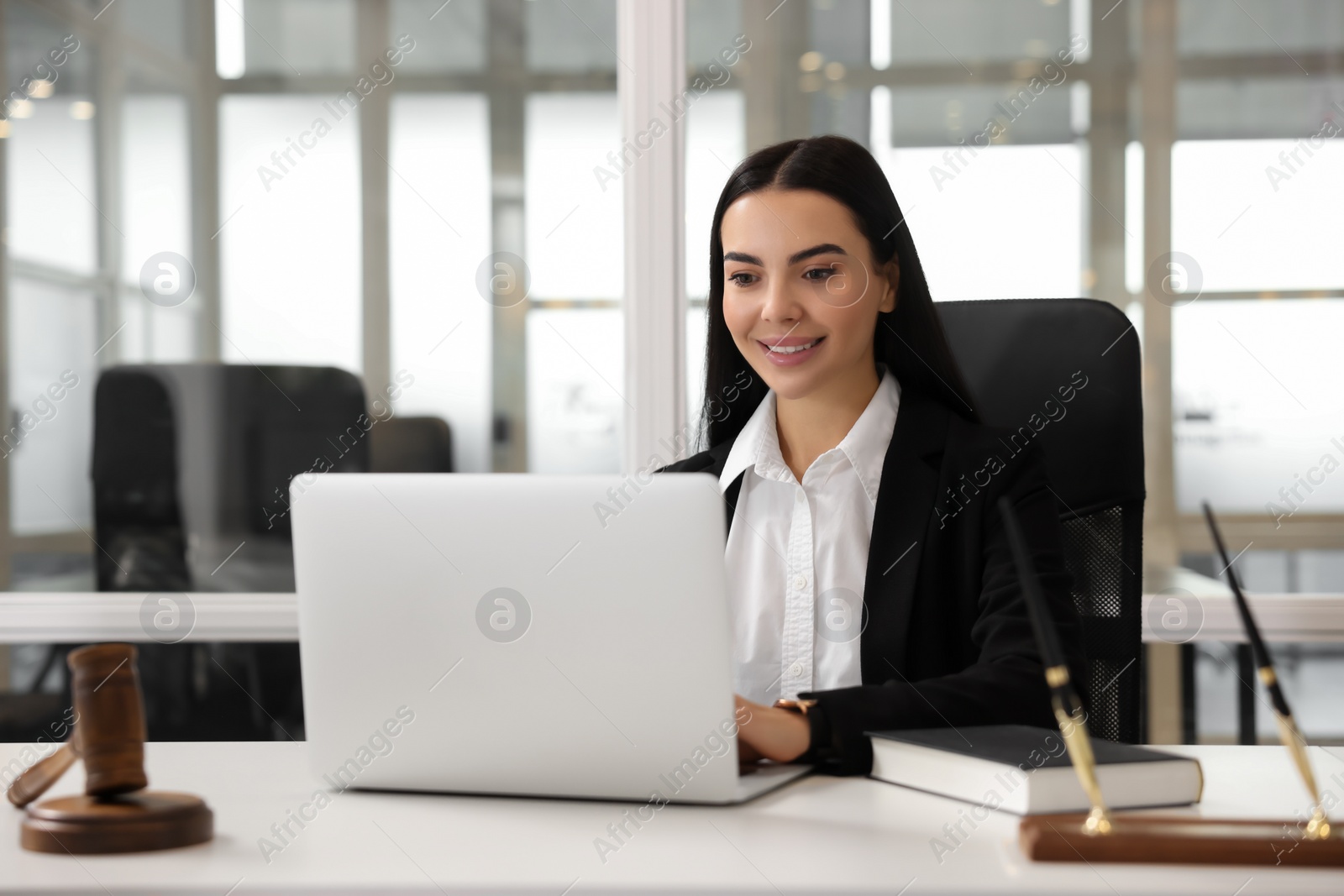 Photo of Smiling lawyer working on laptop in office