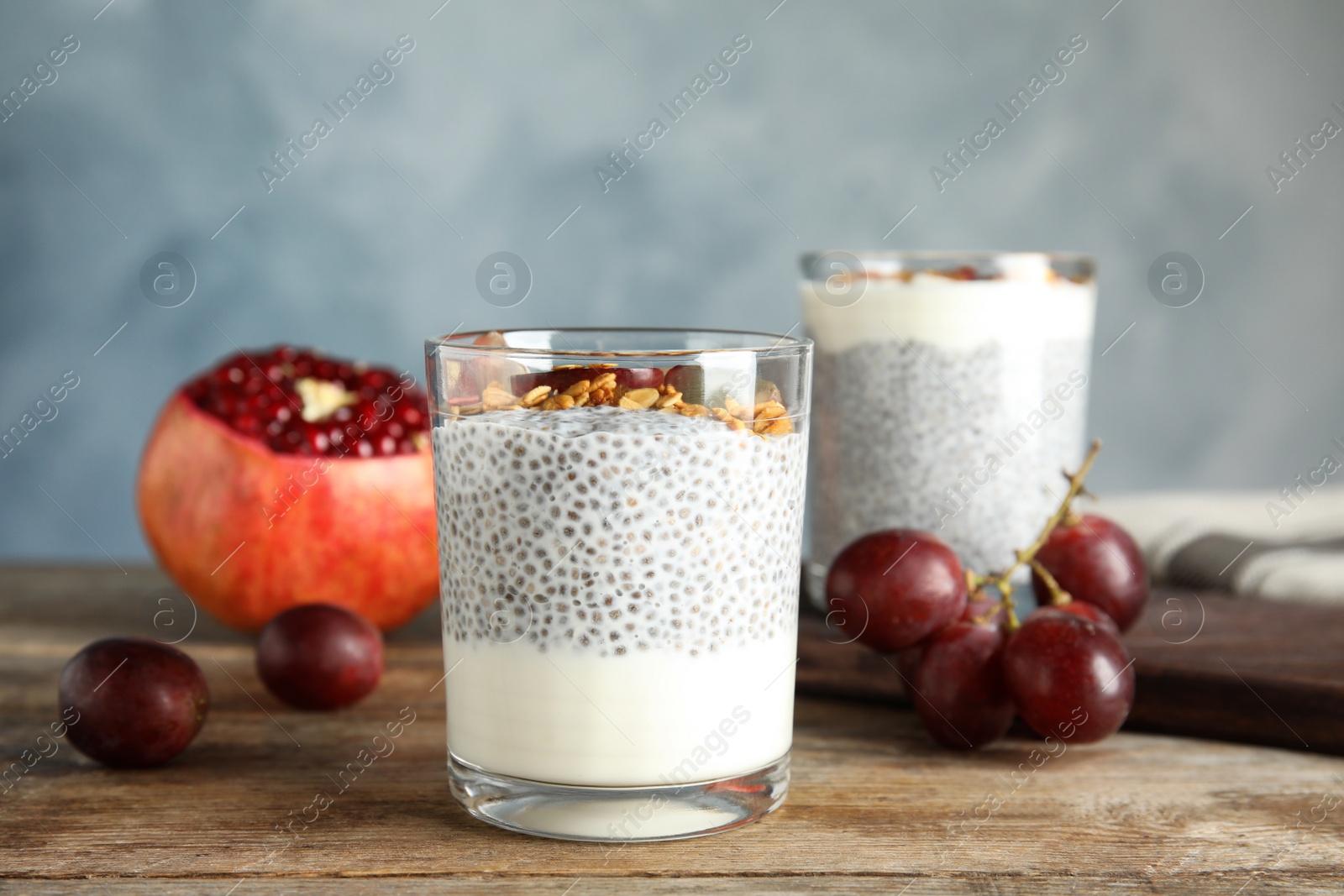 Photo of Tasty chia seed pudding with granola and ingredients on table