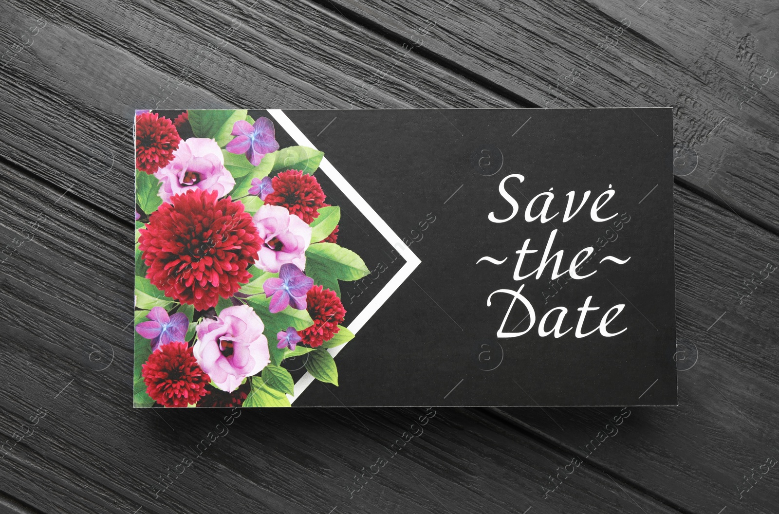 Photo of Beautiful wedding invitation card with Save the Date phrase on black wooden table, top view