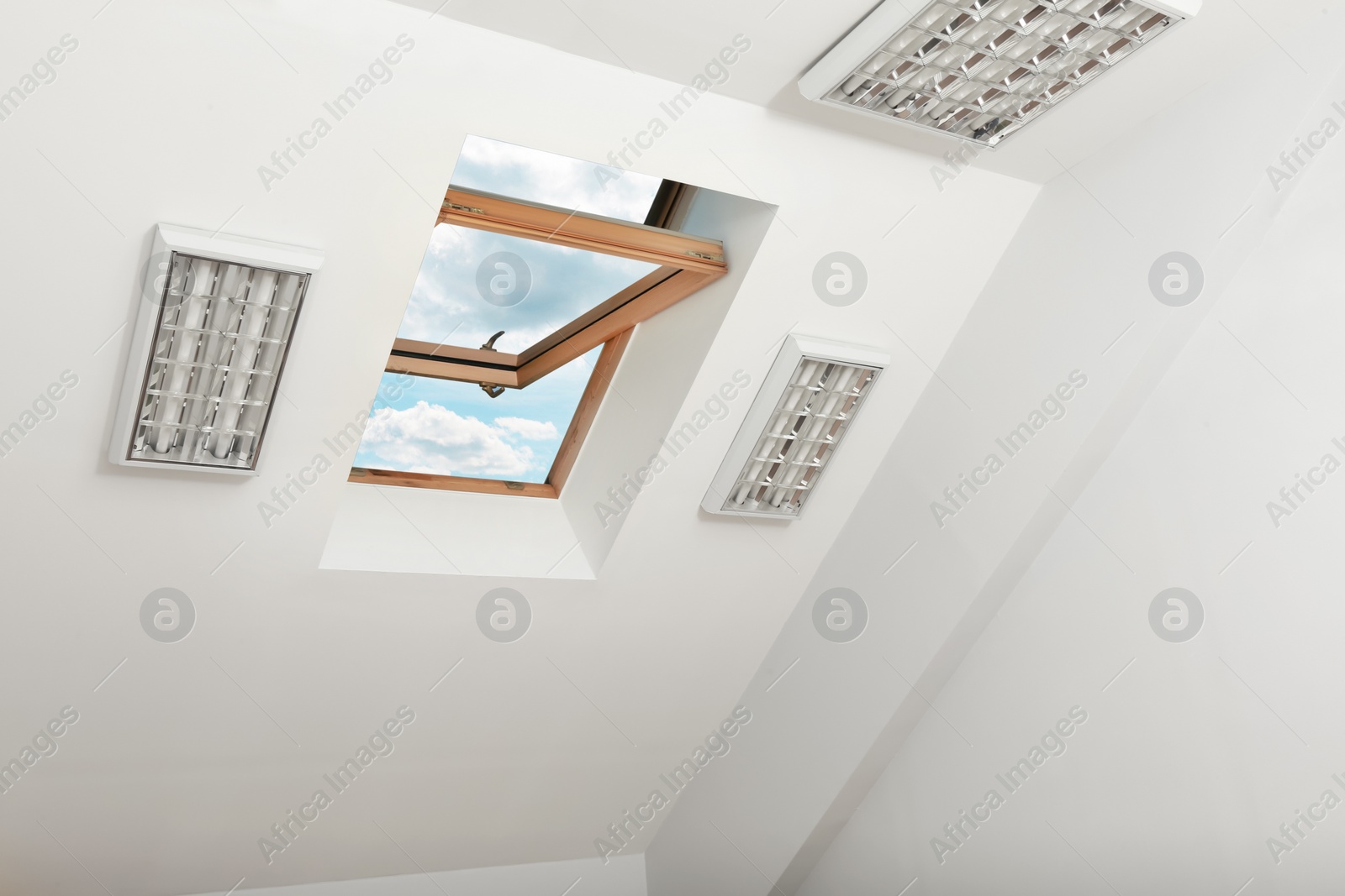 Photo of Open skylight roof window on slanted ceiling in attic room, low angle view