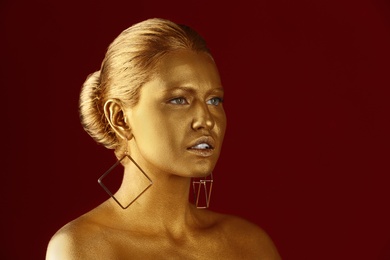 Portrait of beautiful lady with gold paint on skin against color background. Space for text