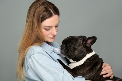 Photo of Woman hugging cute French Bulldog on grey background