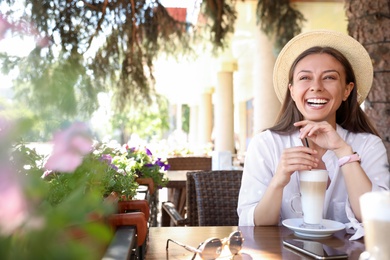 Photo of Beautiful young woman with coffee at table in outdoor cafe