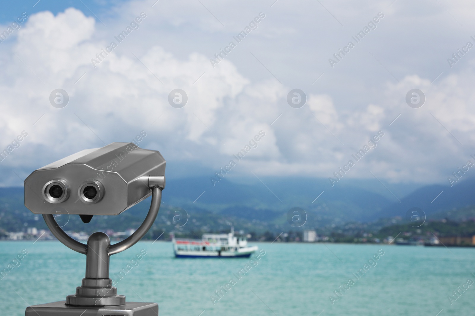 Photo of Metal tower viewer installed near sea, space for text. Mounted binoculars