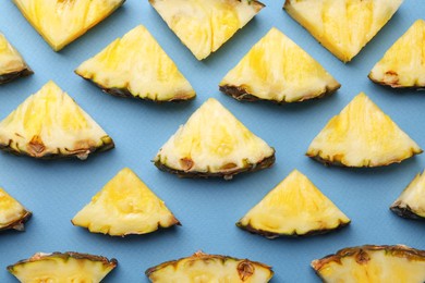 Photo of Pieces of tasty ripe pineapple on light blue background, flat lay