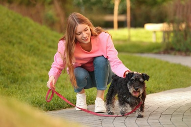 Photo of Young woman with Miniature Schnauzer dog in park