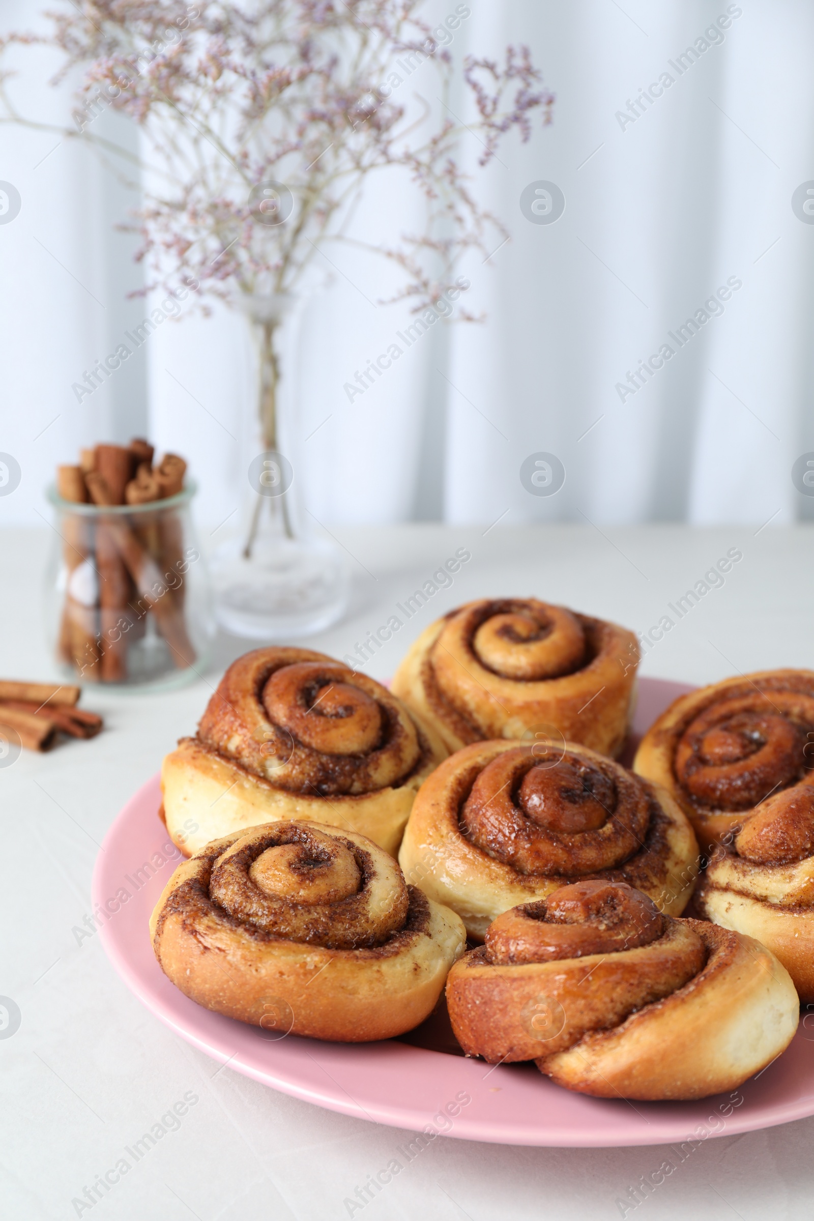 Photo of Many tasty cinnamon rolls on white table, closeup. Space for text