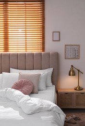 Photo of Cozy bed with soft linens in light room