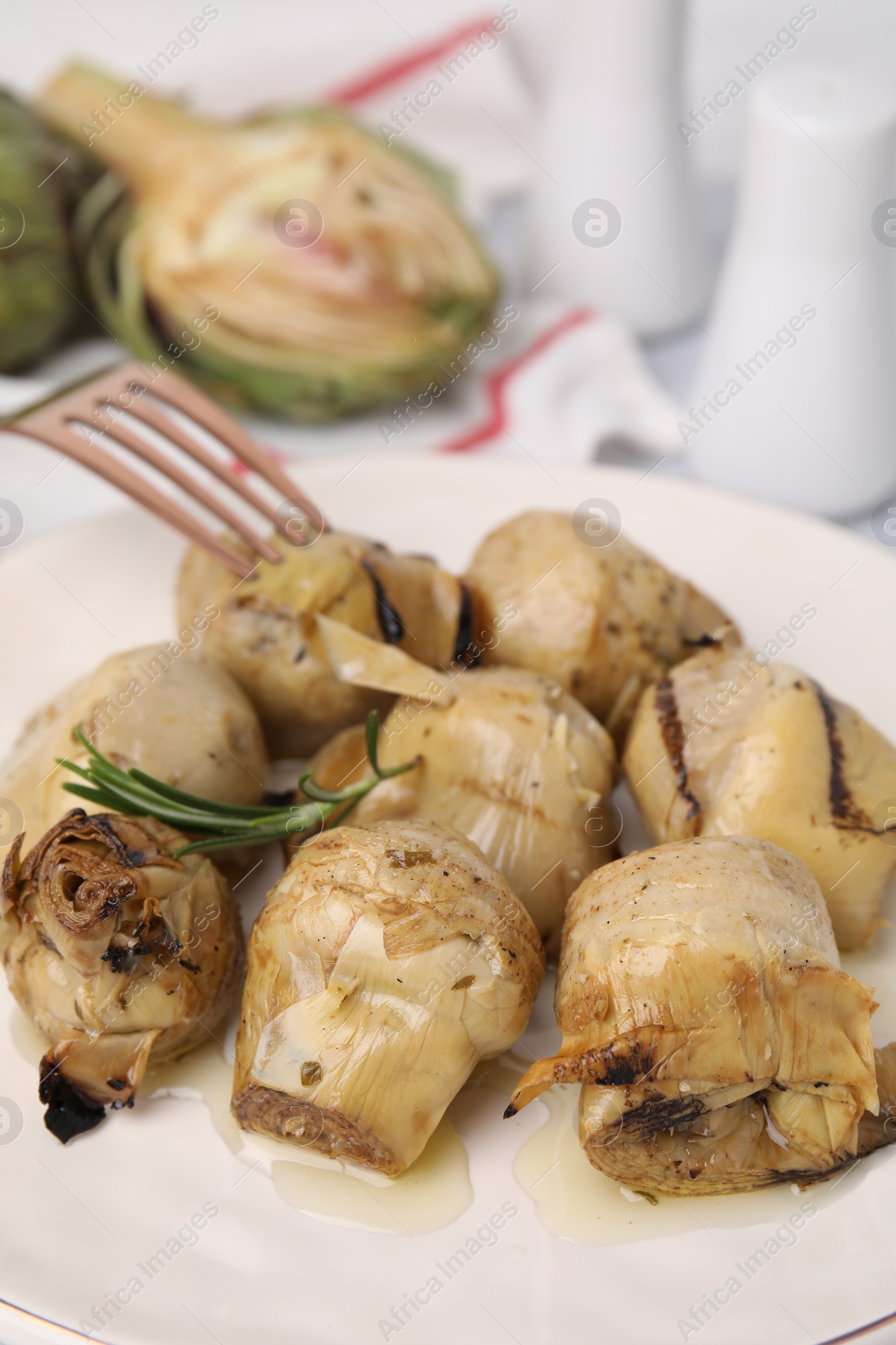 Photo of Delicious pickled artichokes with rosemary on plate, closeup